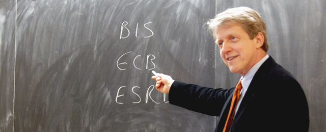 Robert Shiller gesturing in front of a blackboard in a classroom.
