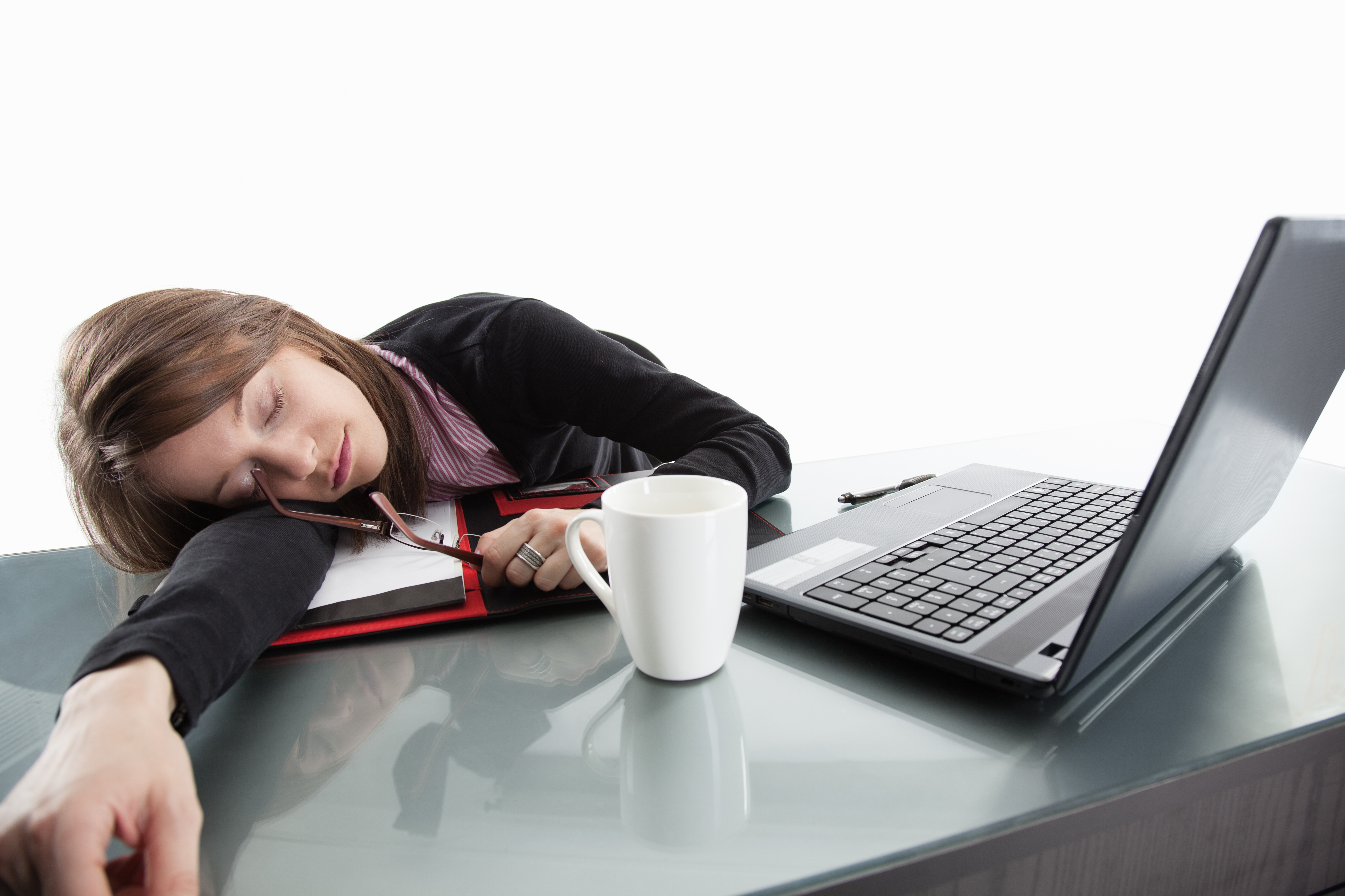 A student passed out on a book in front of a laptopa and a cup of coffee, representing someone who failed at avoiding burnout in business school.