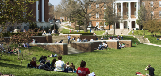 Students sitting and studying on the Mall with McKeldin Library and Jimenez Hall in the background.