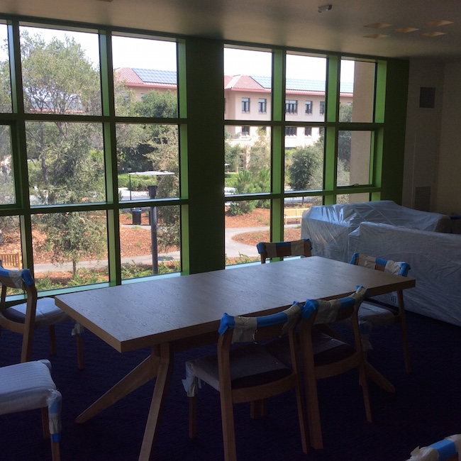 A dining/living room on the second floor looking out on the Knight Management Center which houses the classrooms, offices, and academic facilities of Stanford Graduate School of Business.