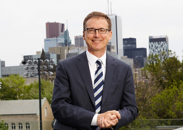 Image of Tiff Macklem, the dean of the University of Toronto's Rotman School of Management, wearing a suit and tie with the Toronto skyline in the background.